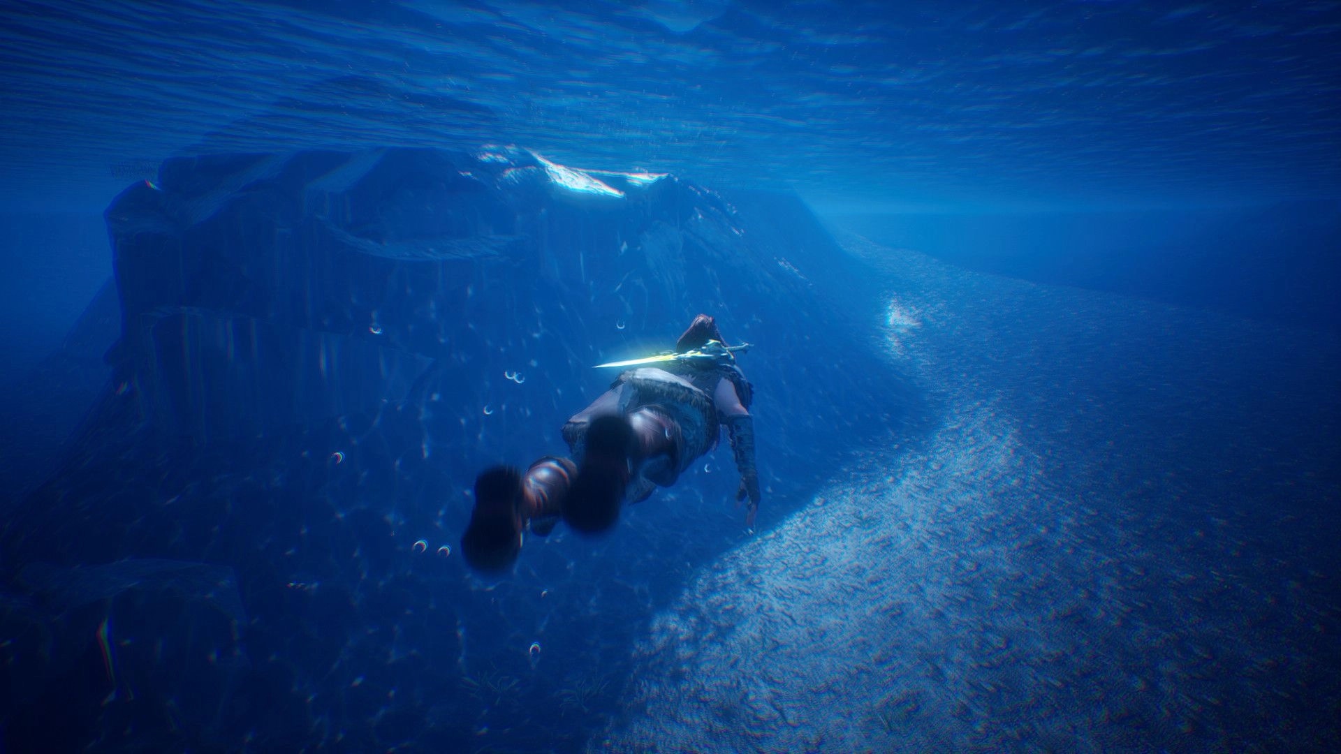 Luminary: Third-person adventurer swims underwater past a rocky cliff, sword strapped on back.