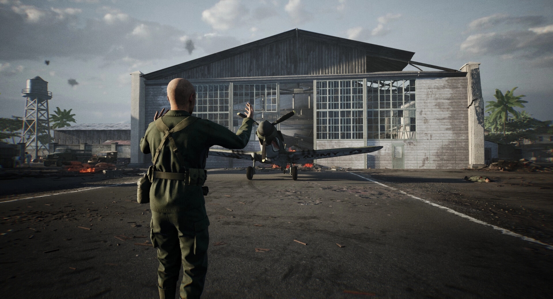 Medic: Soldier waves at fighter plane outside damaged hangar with debris and palm trees nearby
