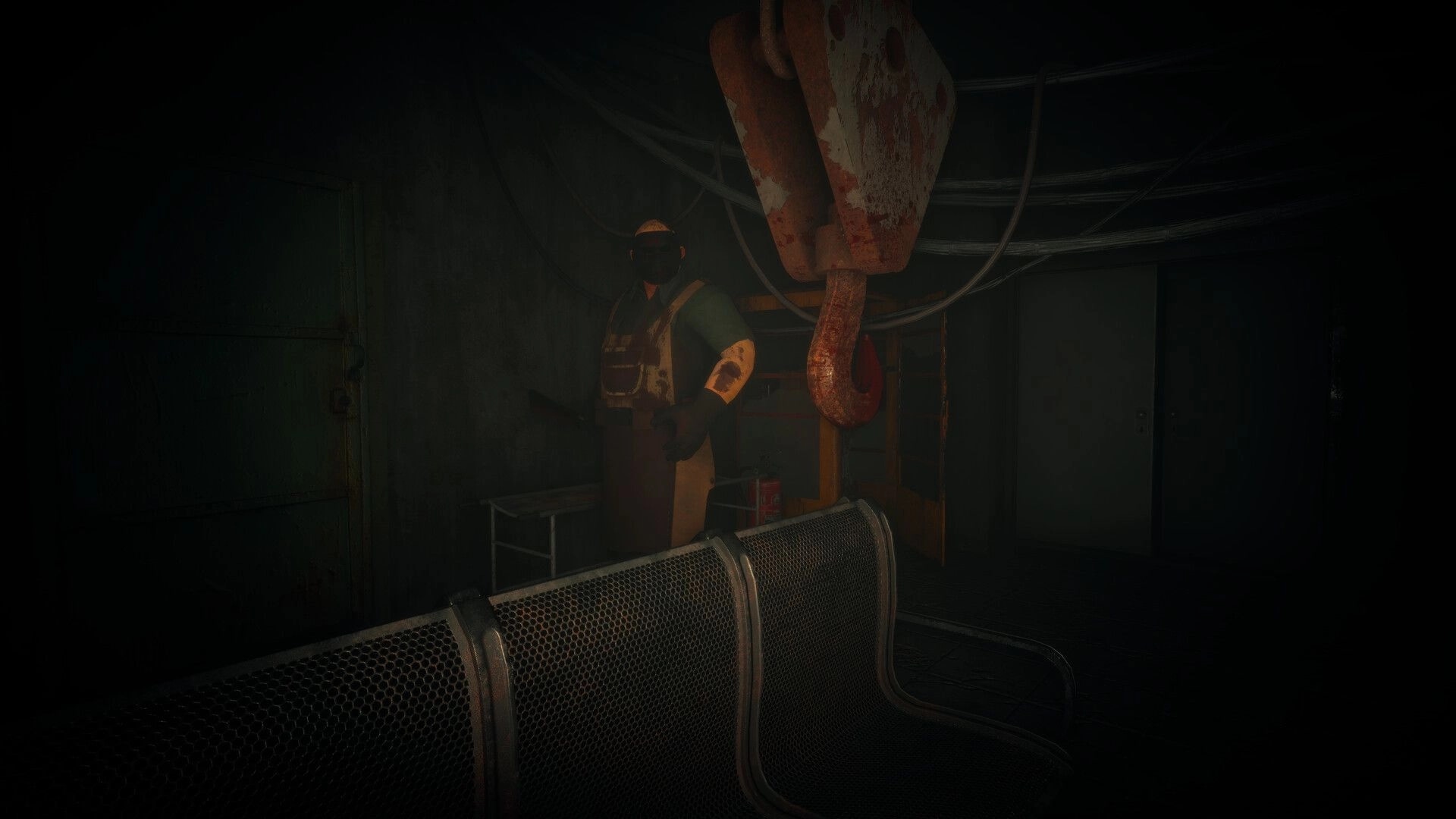 Menthal: Masked worker stands by bloody crane hook in a dim industrial room with metal benches.