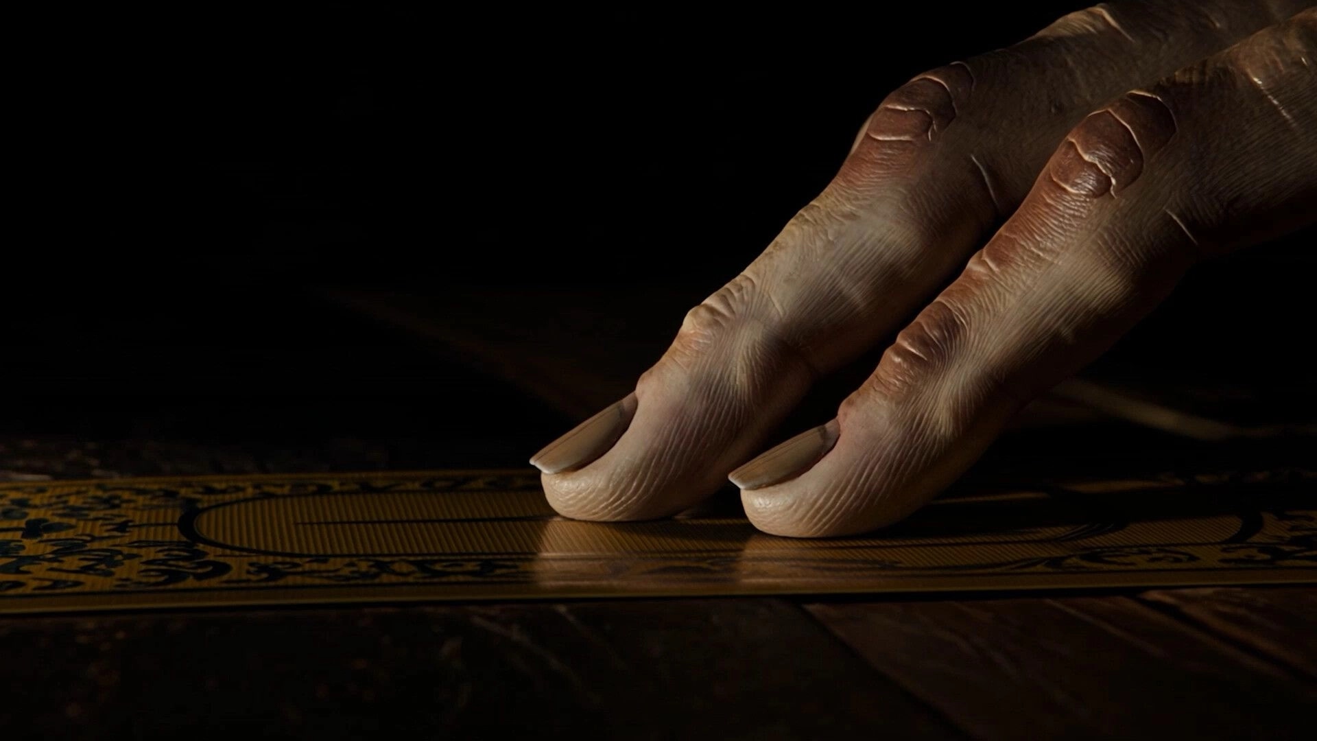 Michael Test: Close-up of a hand pressing fingers on an ornate board in a dark room.