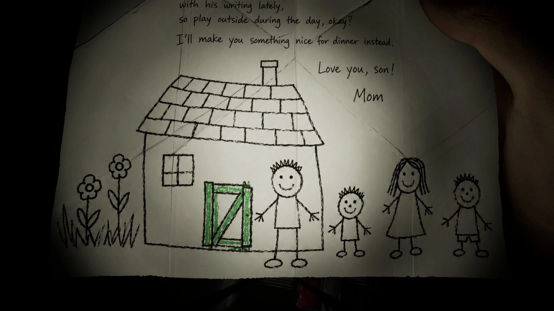 Michael Test: Close-up of a crayon family house drawing with note signed Mom, held in hands.