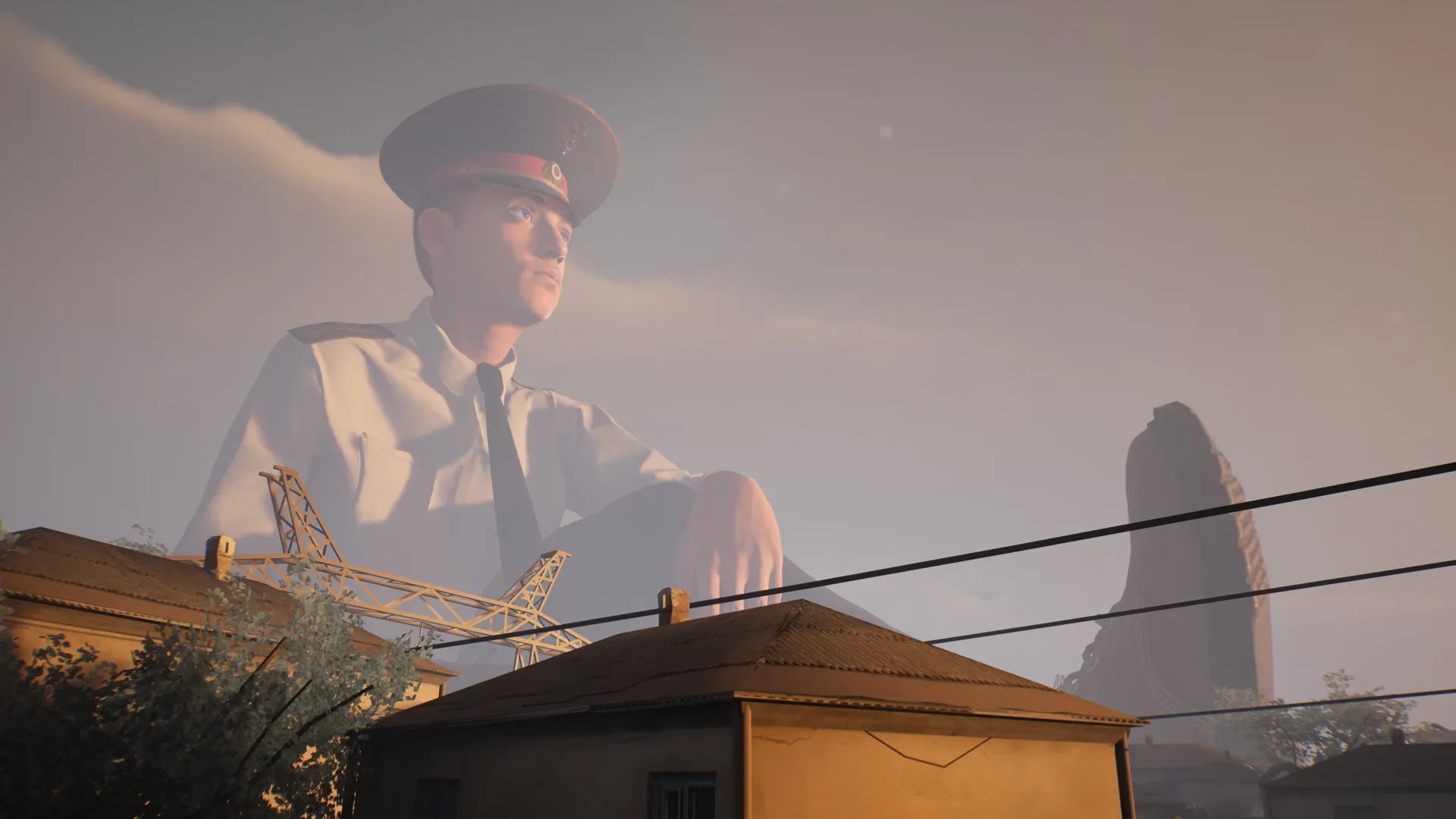 Militsioner: Colossal Policeman kneels over rooftops in a small village setting under a cloudy sky.