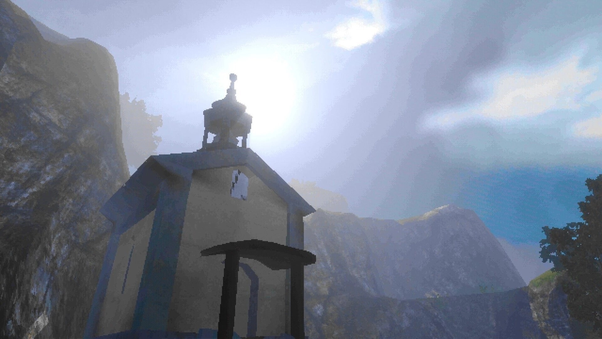 OKUREK: Looking up at a small chapel roof with a bell tower, bright sun over rocky mountains.