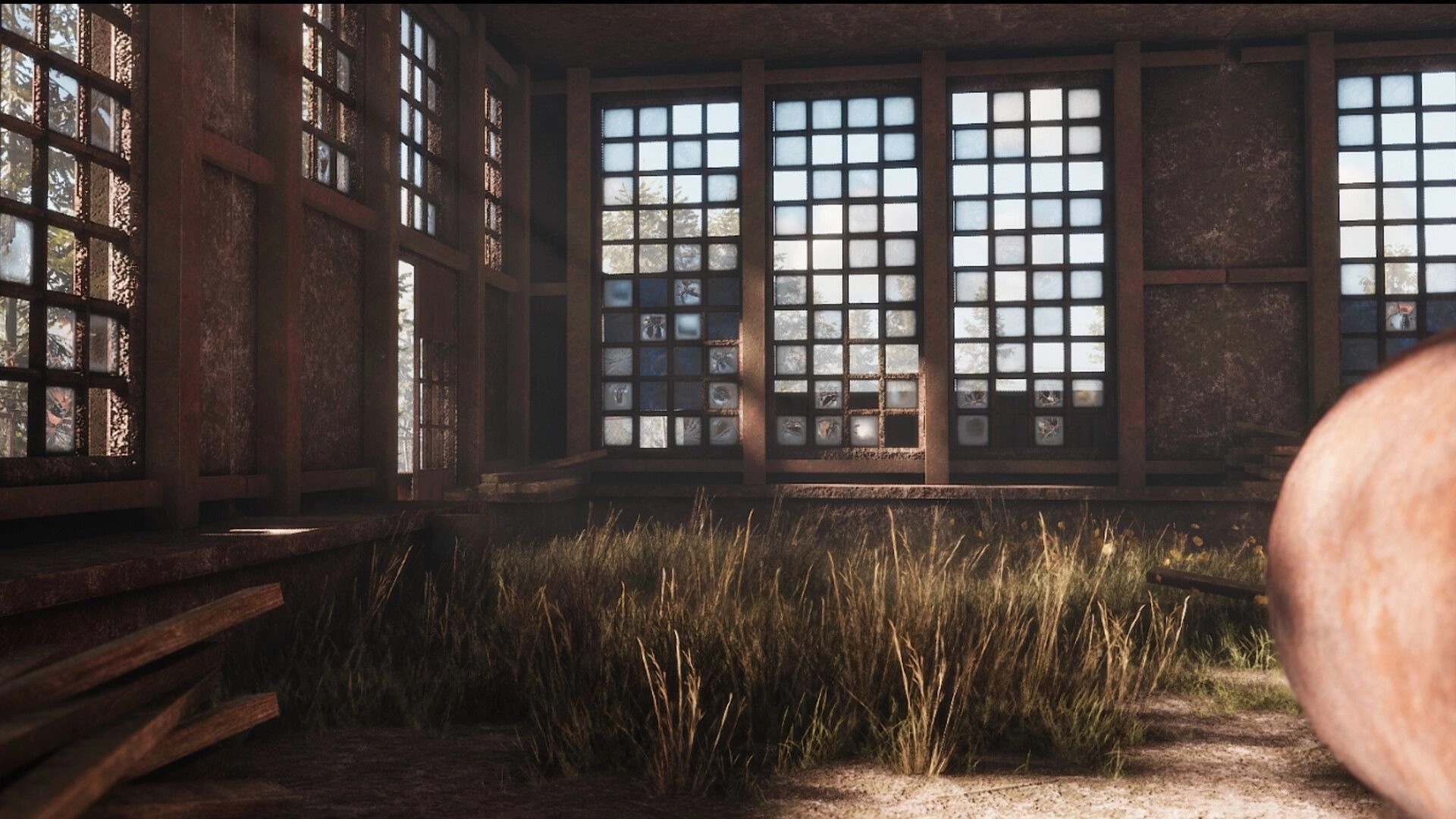 ORMOD: First-person view inside a derelict warehouse with broken windows and tall grass on floor.