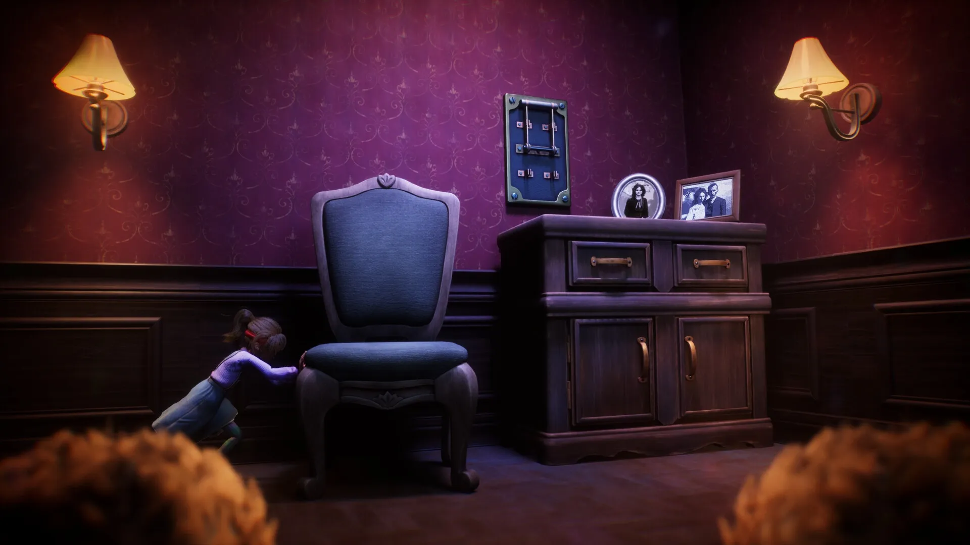 Out of Sight: Sophie hides behind a chair in a dimly lit room with vintage photos and wall lamps.