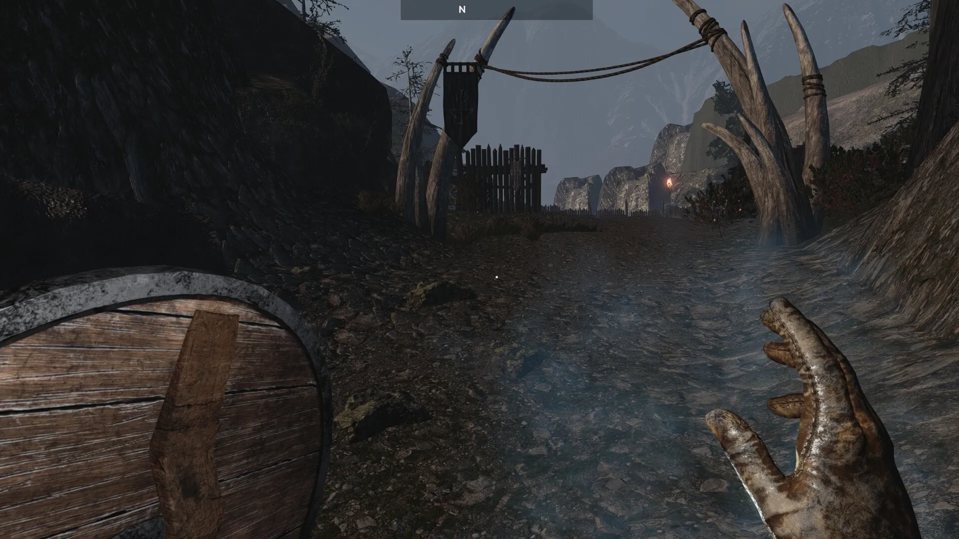 Outwith: Player's hand raised with a shield equipped, approaching a fortified gate in a rocky mountain path