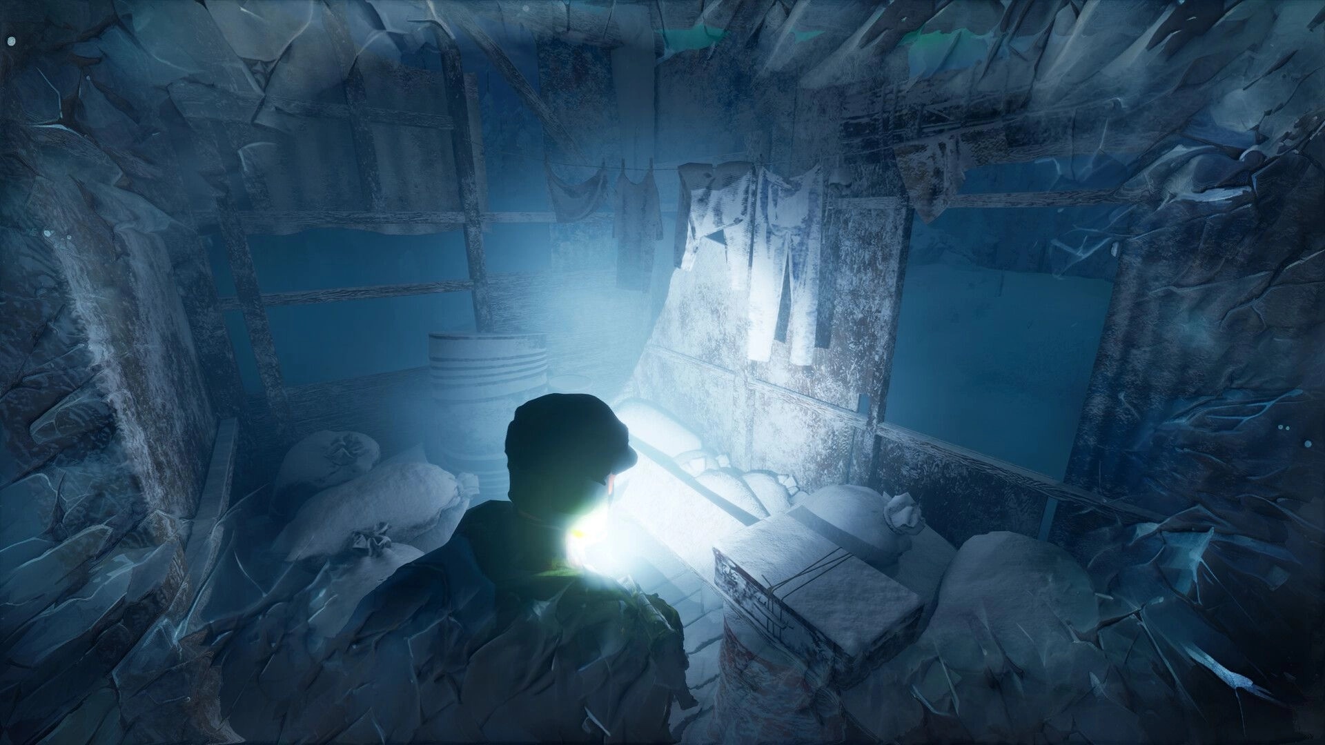 Permafrost: Character explores icy interior with flashlight, revealing snow-covered supplies and clothes