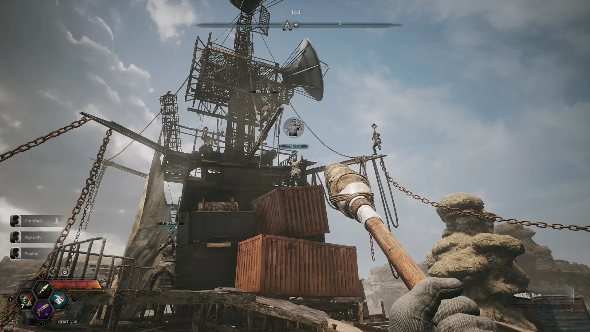 PIONER: Player holding crafted weapon approaches rusted tower with teammates positioned on crates and beams.