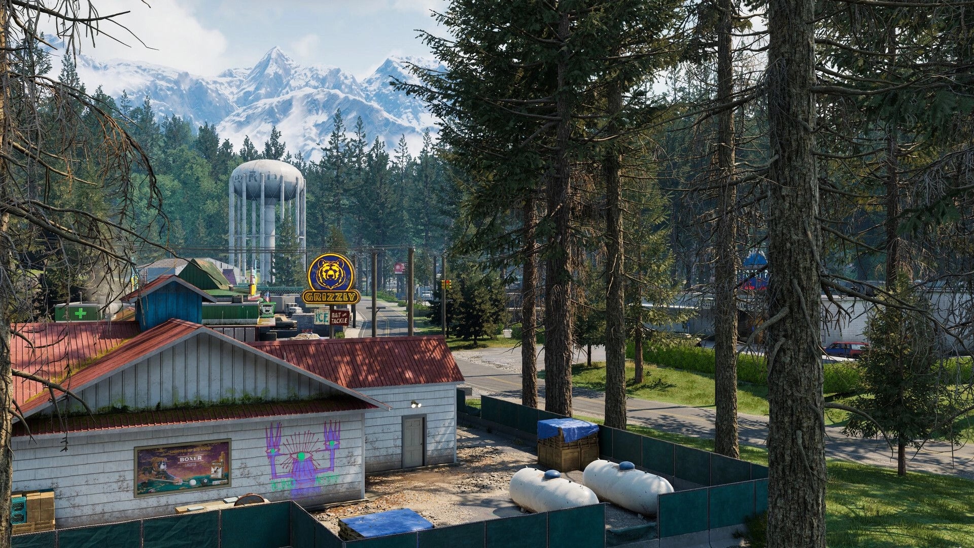PUBG: View over small town roofs and Grizzly sign with water tower, pine forest, snowy peaks.