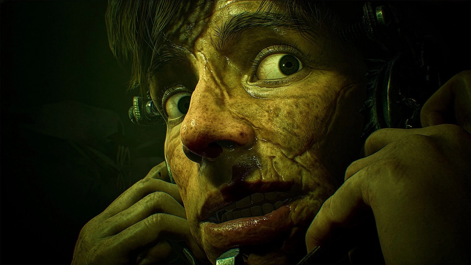 SAW: Close-up of terrified captive with metal head clamps in a dim green-lit torture room.