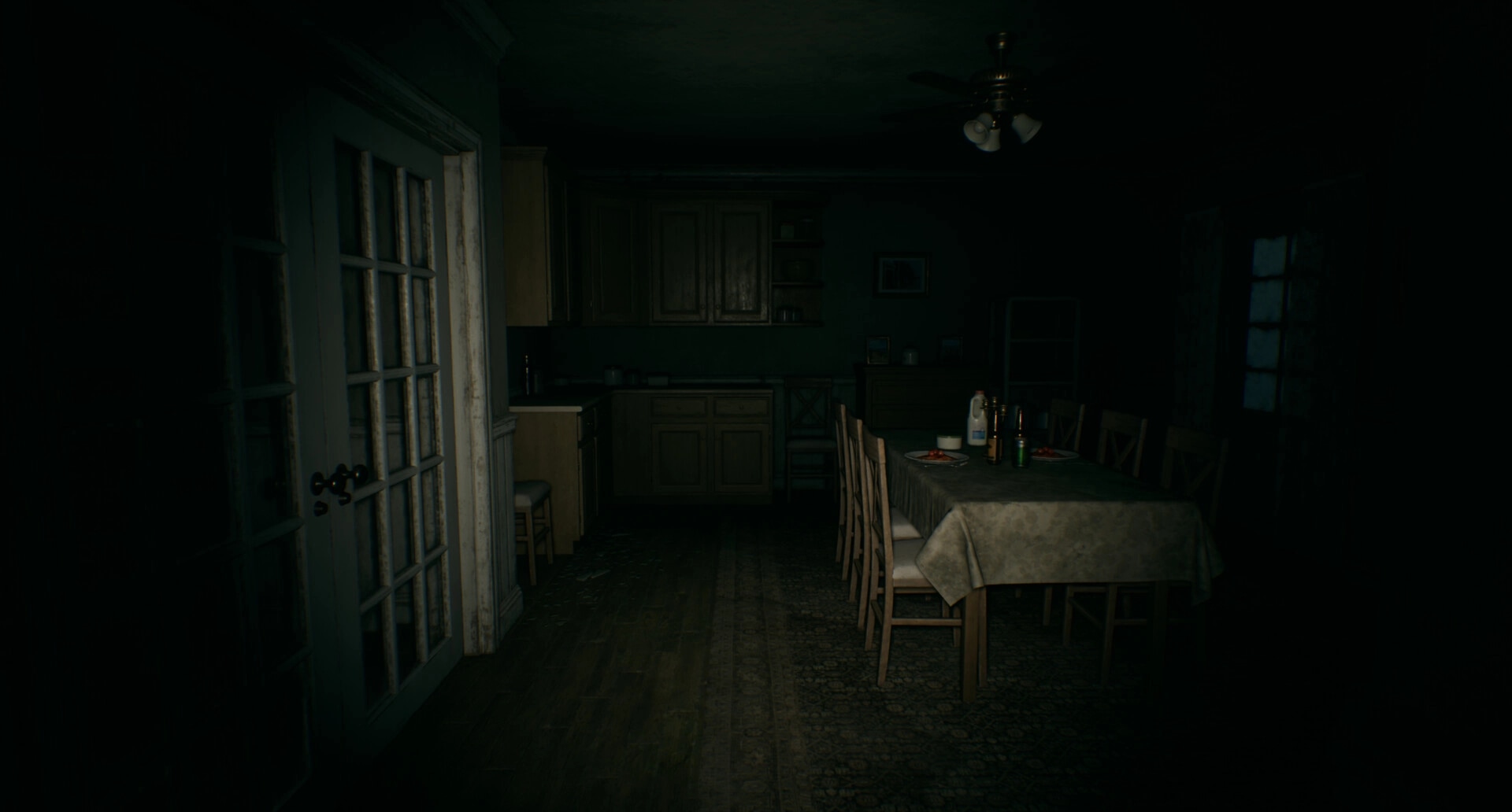 Separated: Dimly lit kitchen with a dinner table set, surrounded by wooden chairs in a shadowy room.