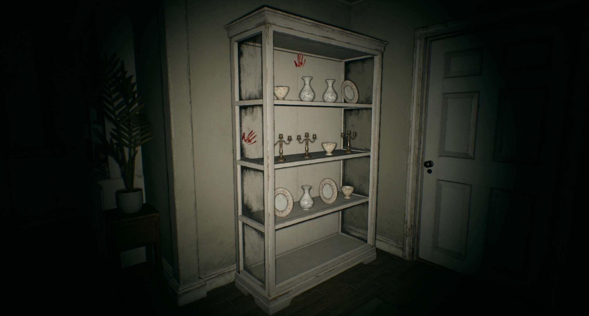 Separated: Bookshelf with vases and red handprints in dimly lit room near closed wooden door