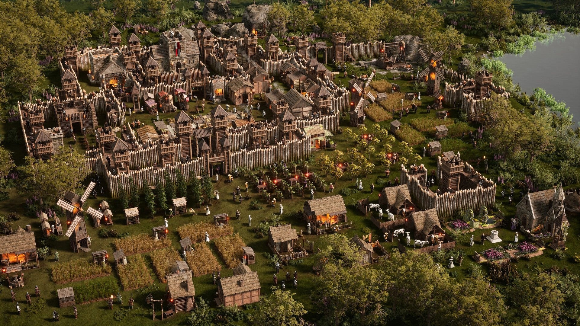 Stronghold 4: Walled village with wooden towers, farms, windmills, and peasants by a riverbank.