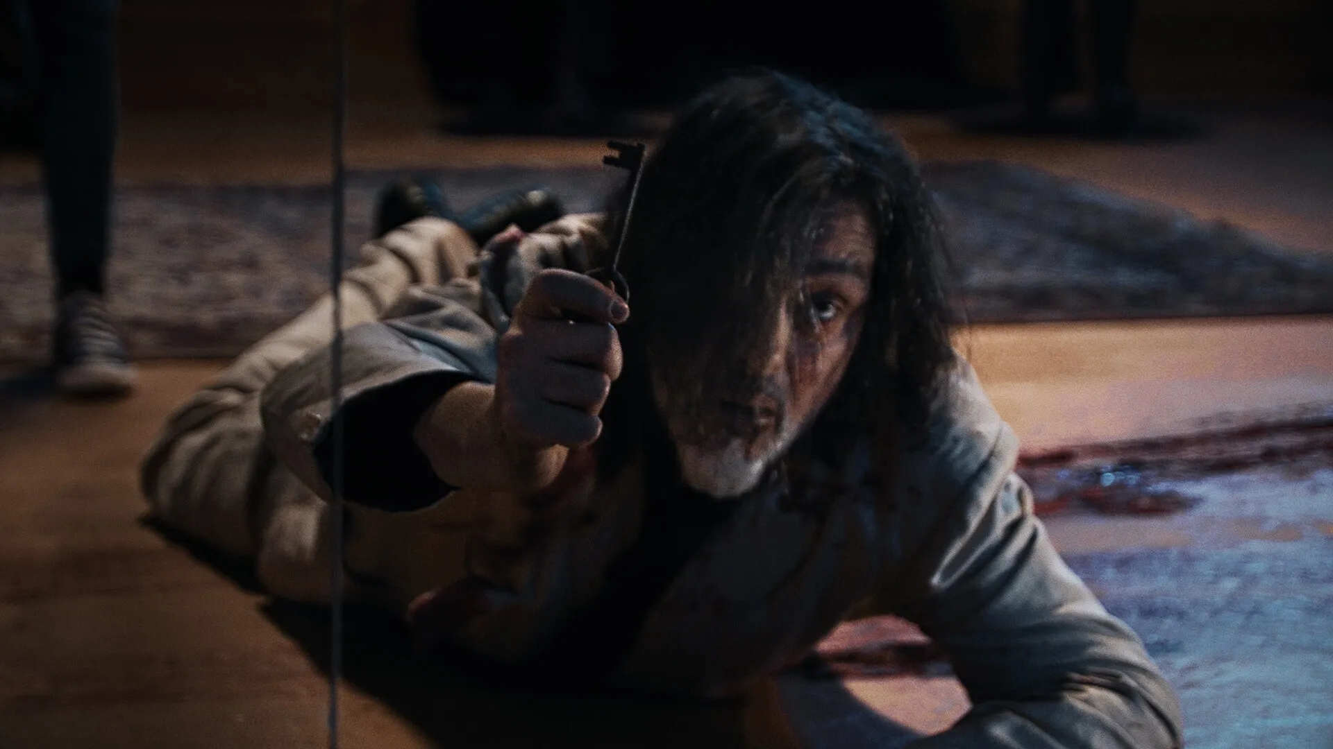 Tenebris Somnia: Man crawling on bloodstained floor holding a key in dimly lit room with rug.