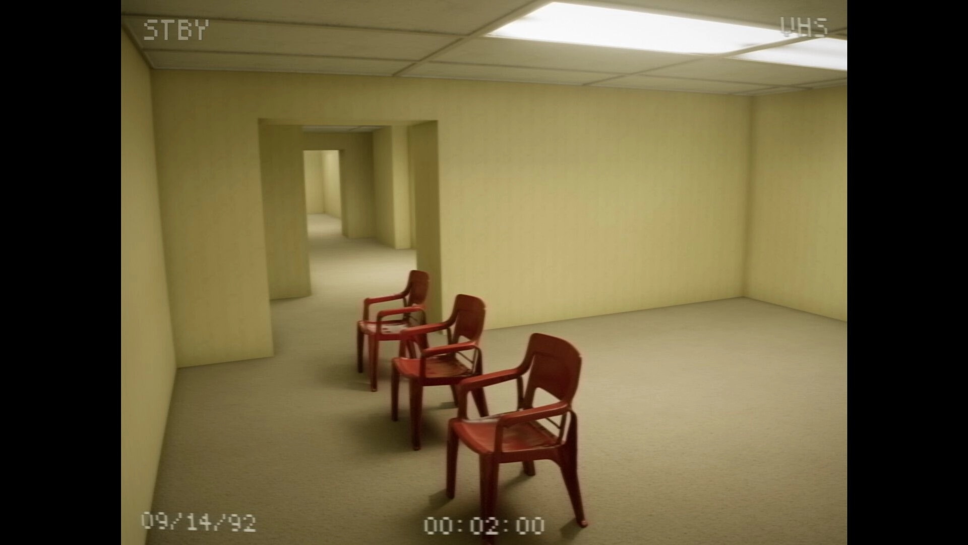 The Backrooms: VHS cam view of empty yellow office corridors with three red chairs under fluorescent lights.