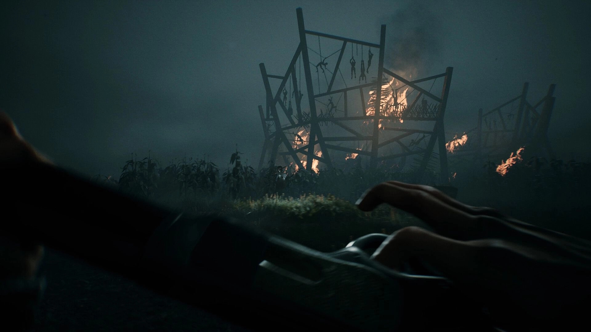 The Bornless: Player holding a shotgun in dark field with burning wooden structure in the background