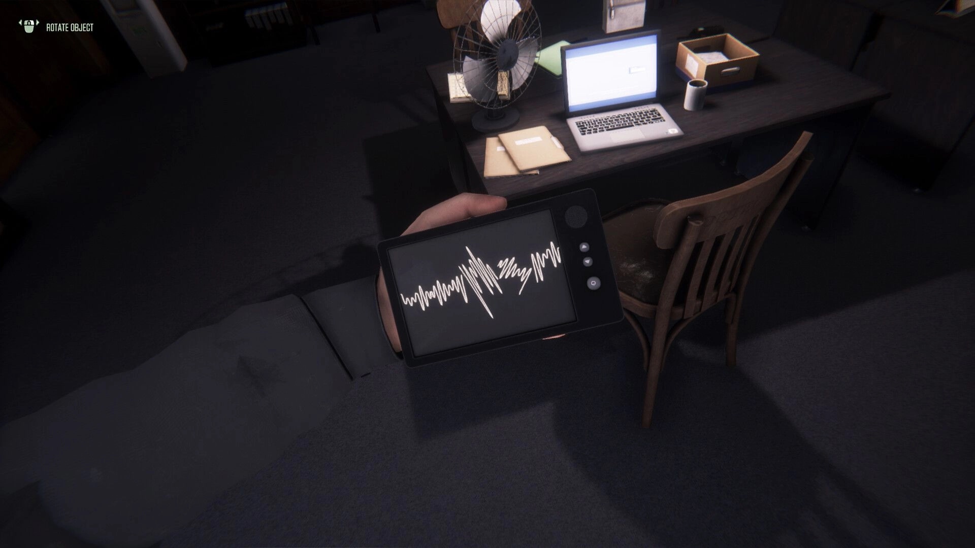 The Enigma Cases: Player examines audio waveform on device in dimly lit office with desk and laptop