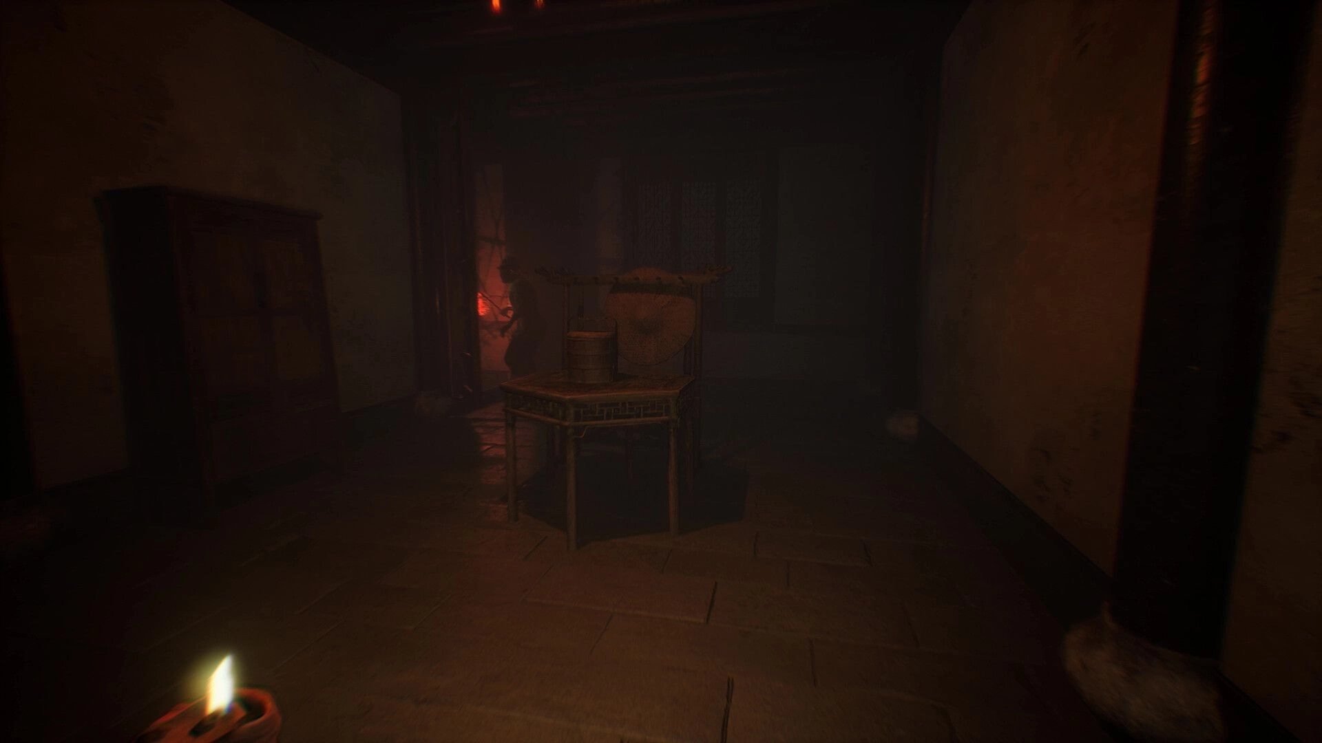 The Grotto Diary: First-person view of a dim corridor with a table and drums, lit by candles and fog.
