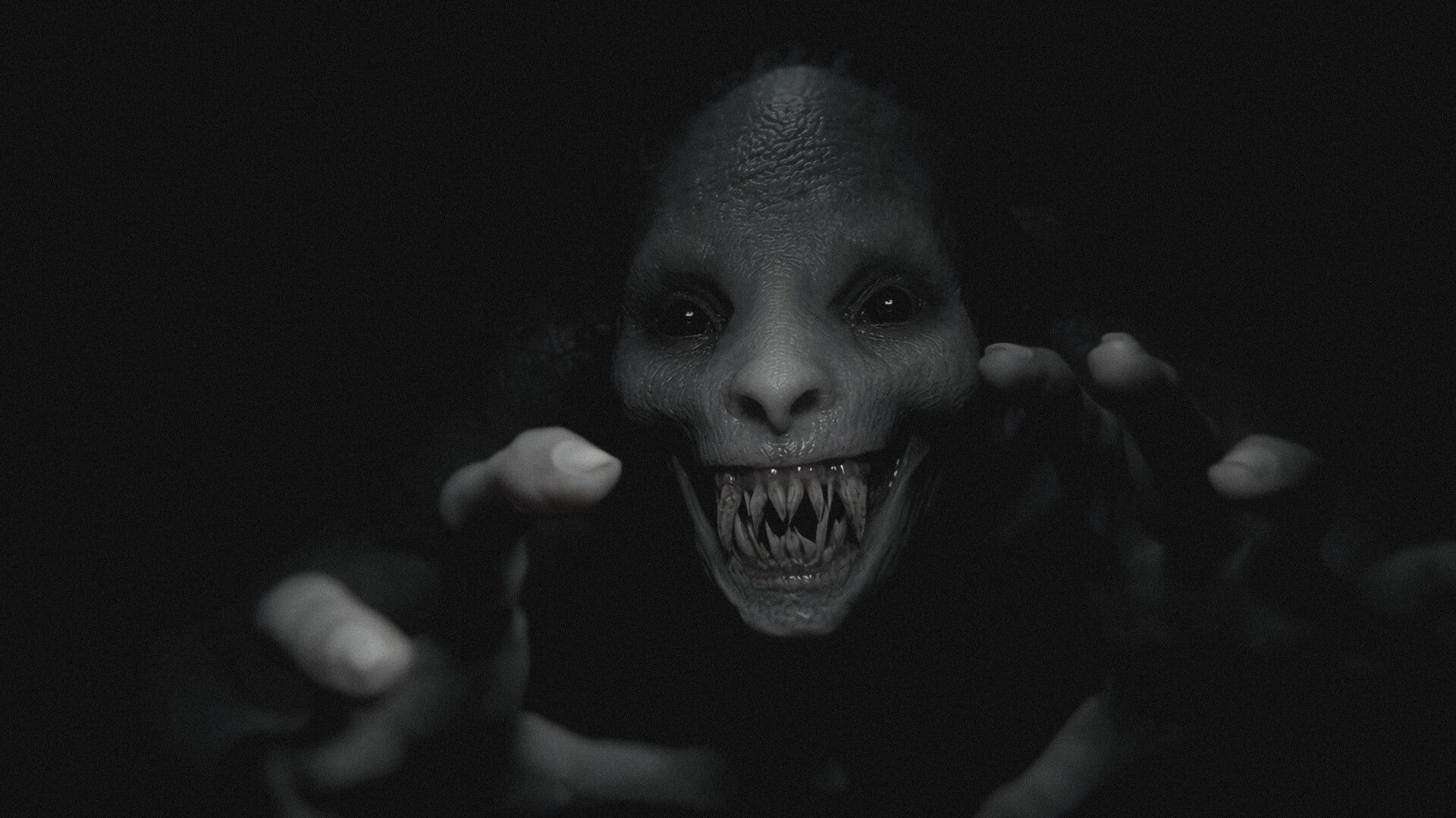 The Unworthy: Fanged demon face lunging toward camera with outstretched hands in darkness.