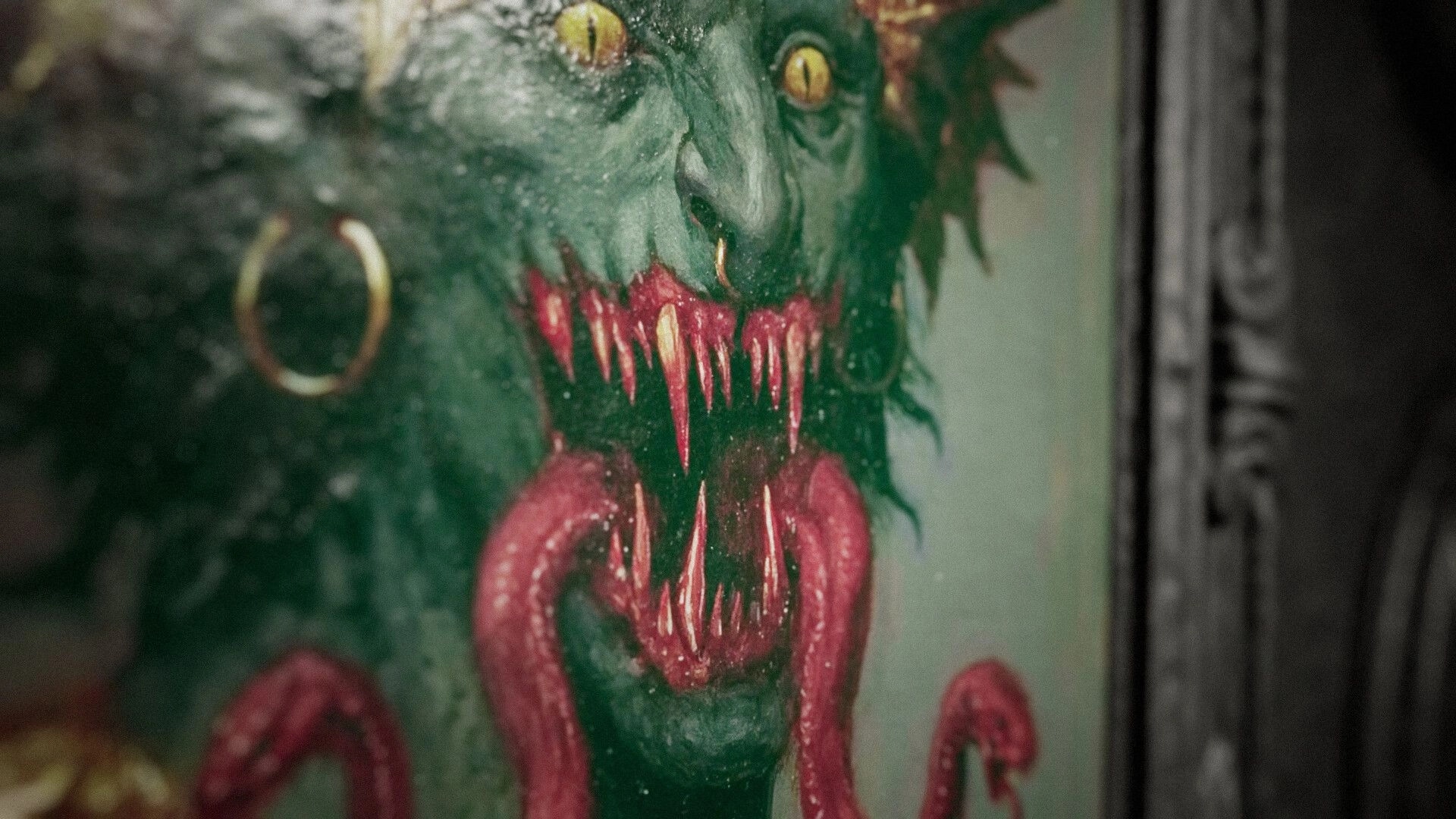 The Unworthy: Close-up of a snarling demon painting with yellow eyes and dripping fangs on a wall.