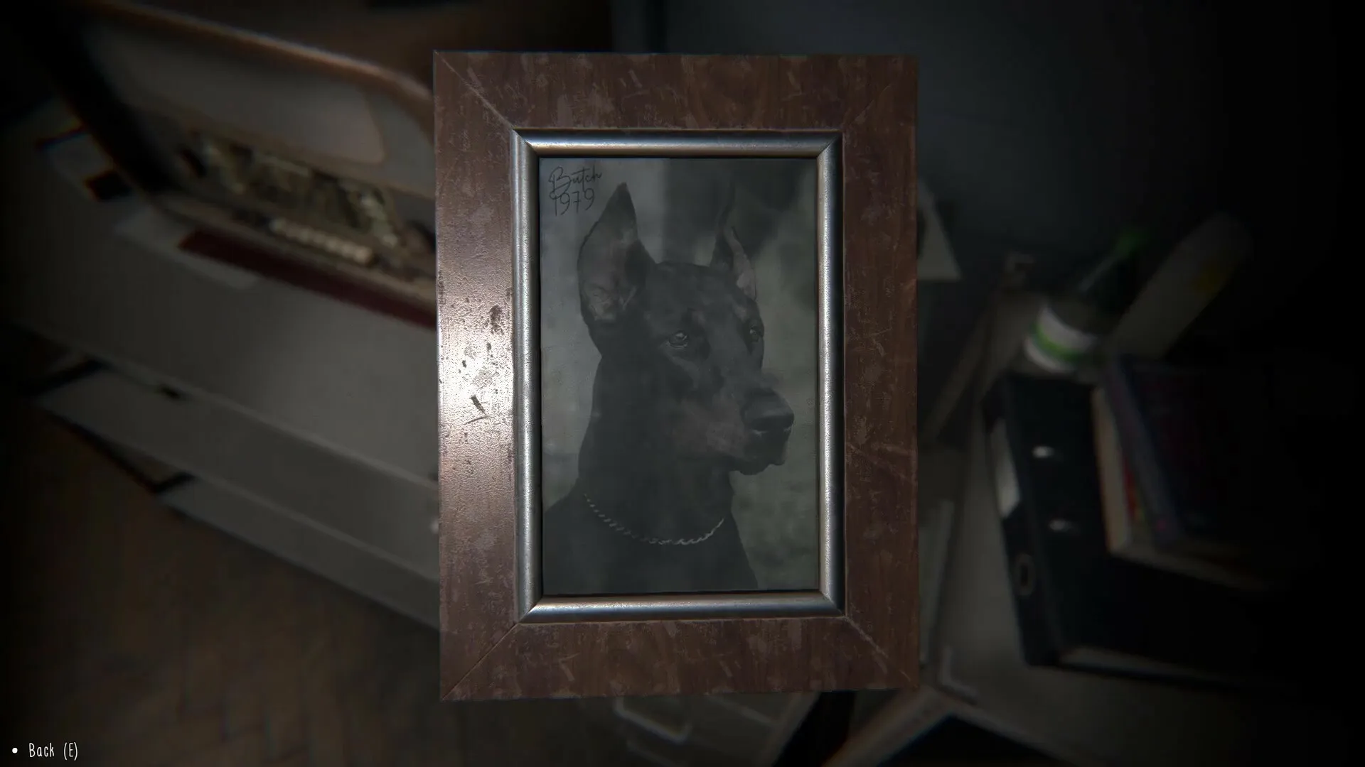TIC-TAC: Framed photo of a Doberman on a desk in a dimly lit room with books and an old TV.
