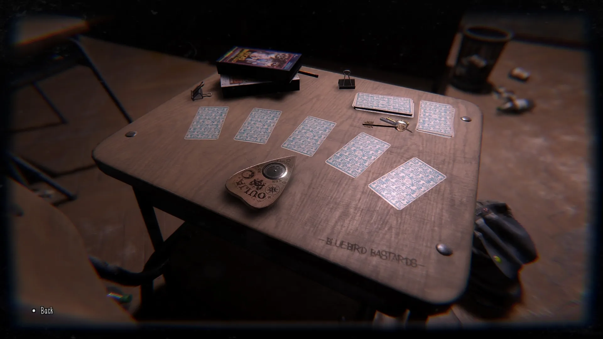 TIC-TAC: Table with tarot cards, Ouija board, and keys in abandoned Bluebird High School classroom.
