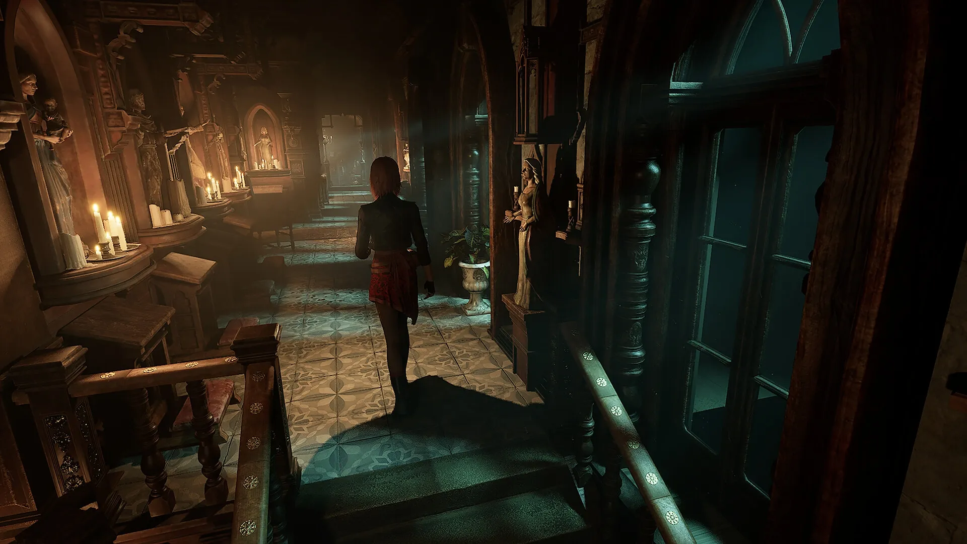 Tormented Souls 2: Caroline Walker explores a dimly lit hallway with statues and candles in Villa Hess
