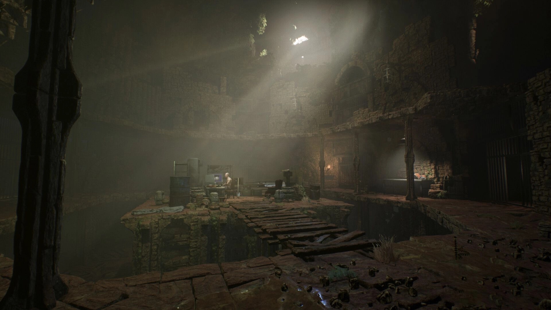 TORMENTOR: Dimly lit dungeon with a lone figure at a computer amidst stone walls and scattered debris.