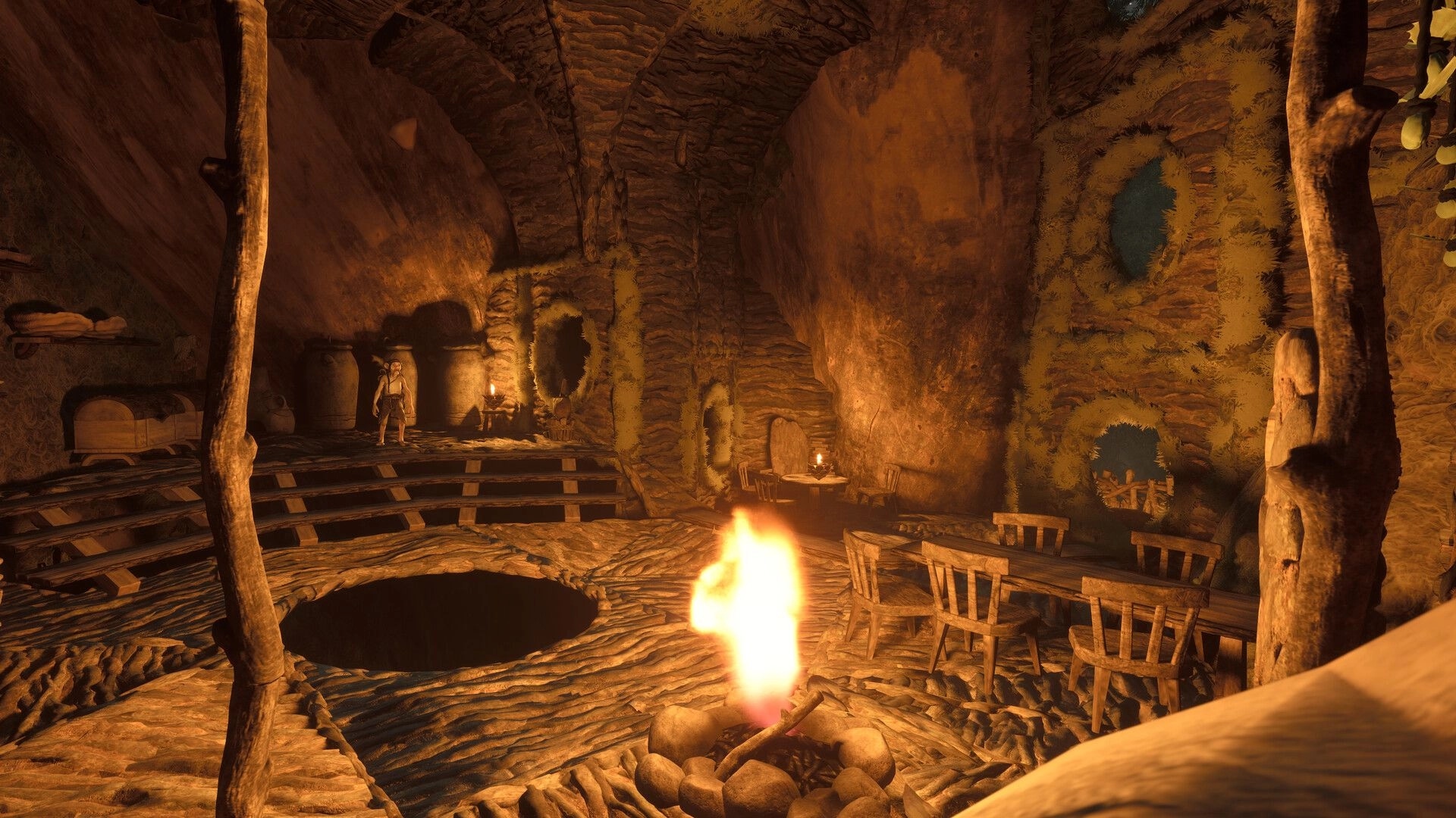 TROLLHEIM: Gnome stands near jars and bed in a warm cave home with campfire, tables and chairs.
