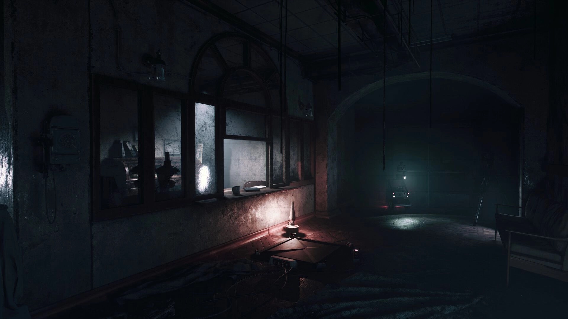 UNHOST: Remote-controlled robot with headlamp rolls down a dark hospital corridor past windows and debris.