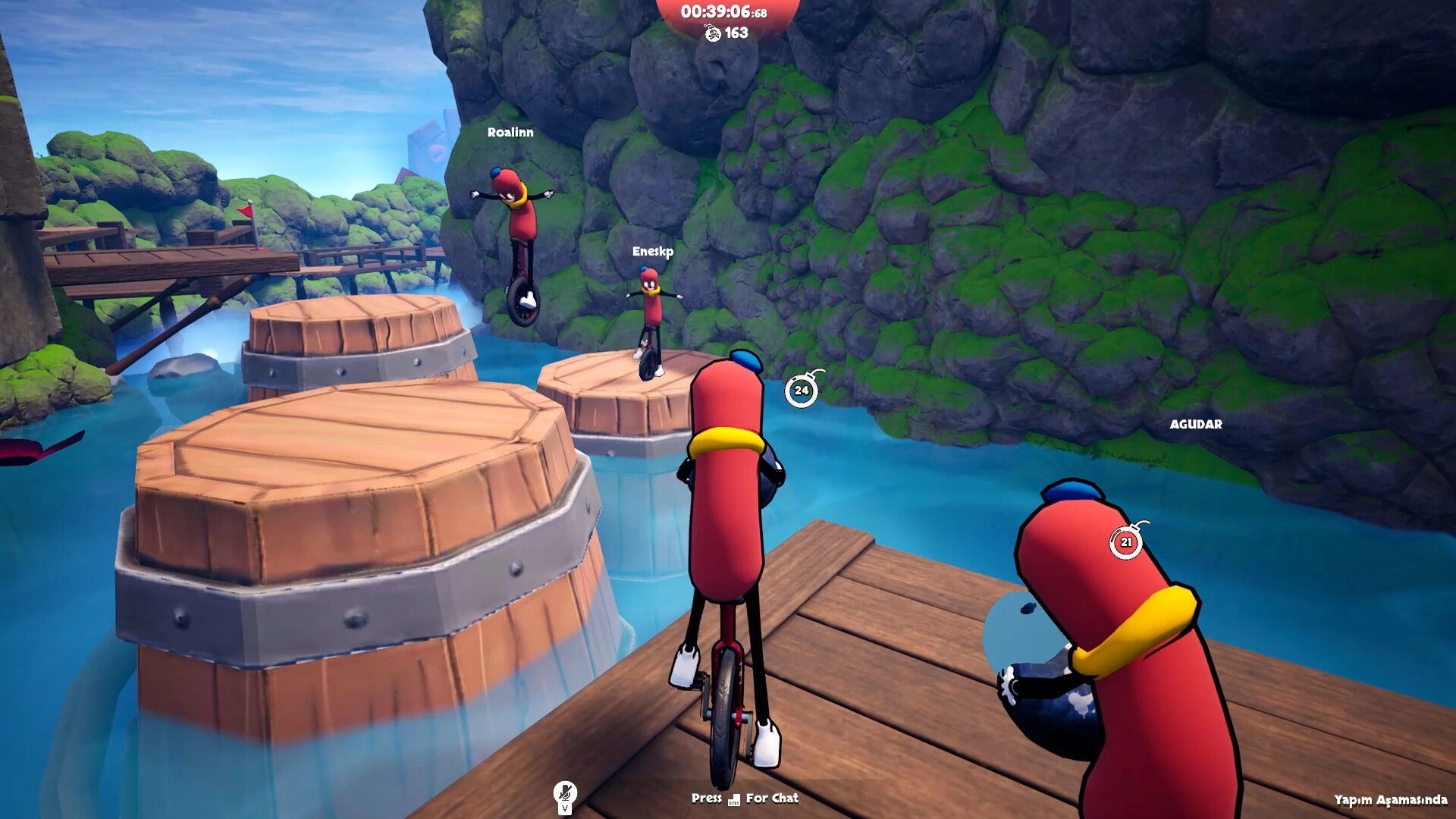 Unicycle Together: Sausage riders hop across barrel platforms over water beside mossy cliffs.