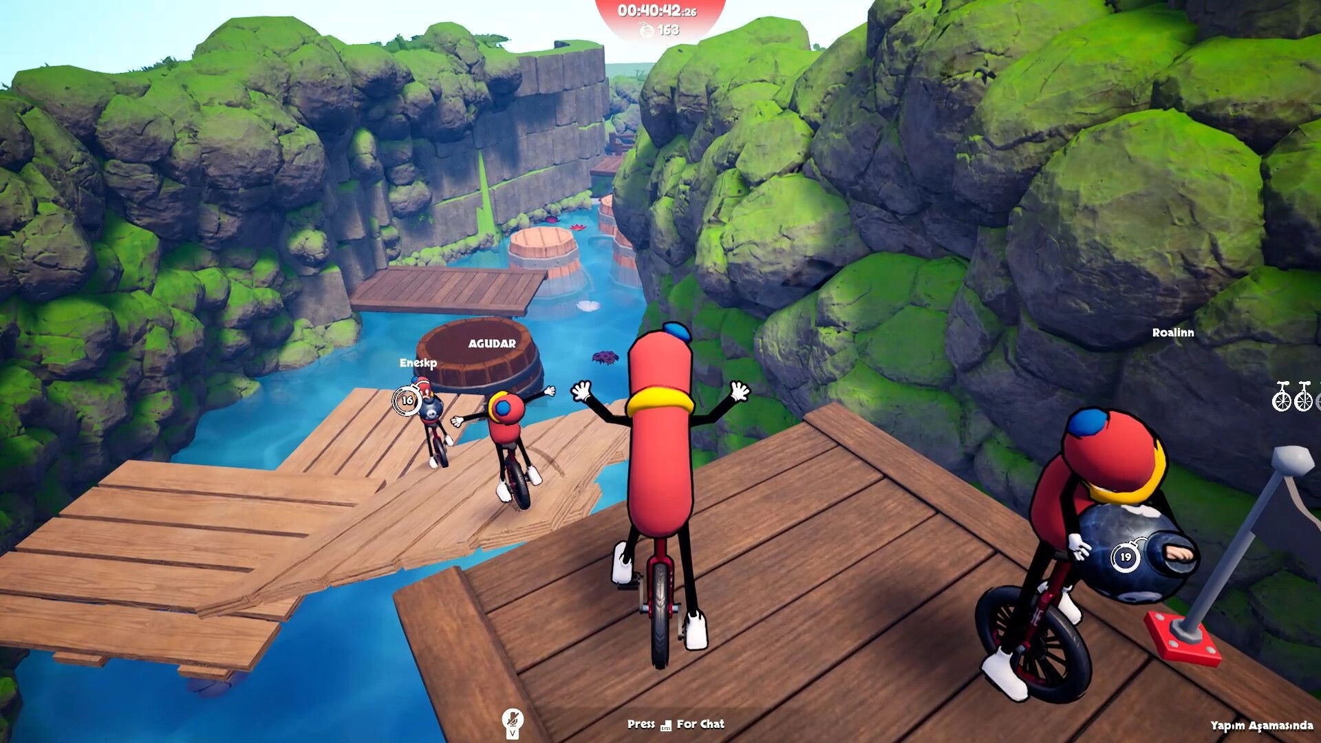 Unicycle Together: Sausage riders balance on planks over river canyon, one holds bomb timer UI visible.