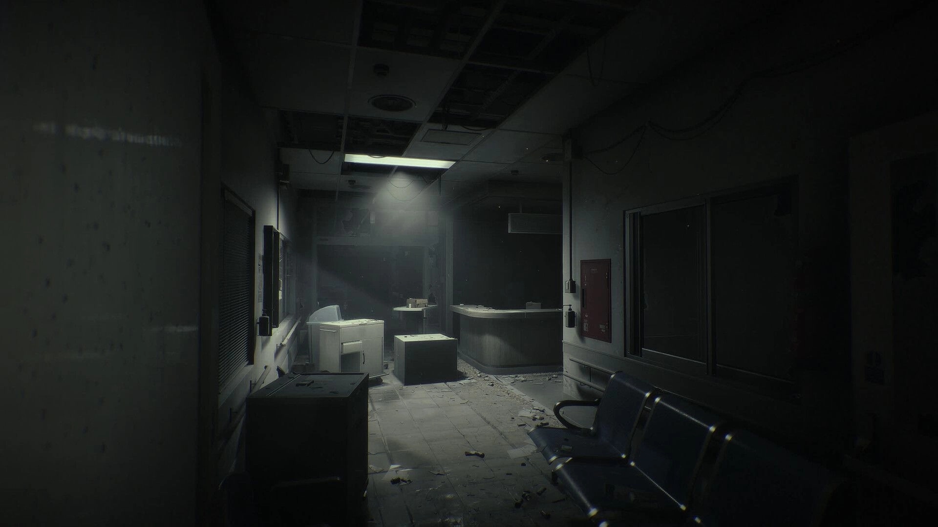 Unlisted: Empty hospital corridor with dusty reception desk, debris-strewn floor, and dim lights.