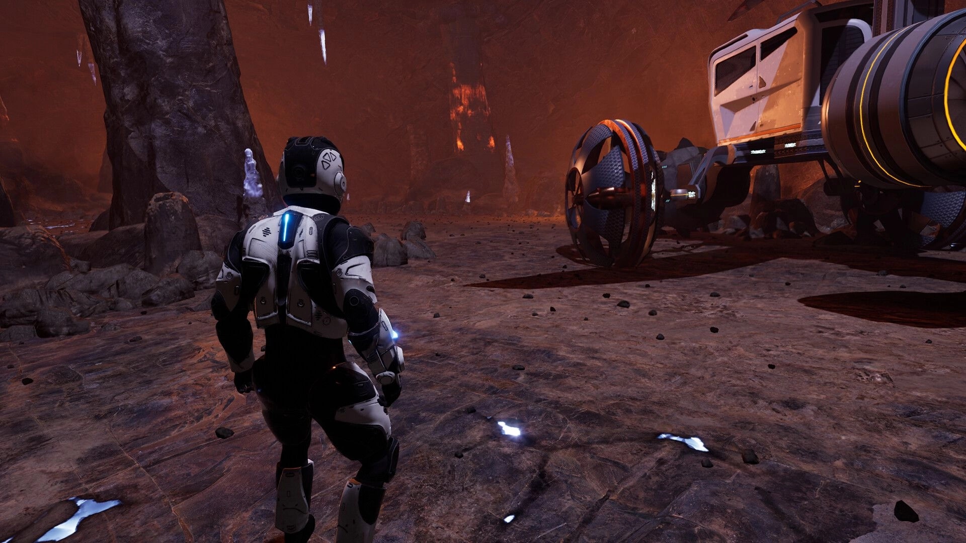 Venus: Player in futuristic suit explores rocky cavern with a large, advanced mining vehicle nearby