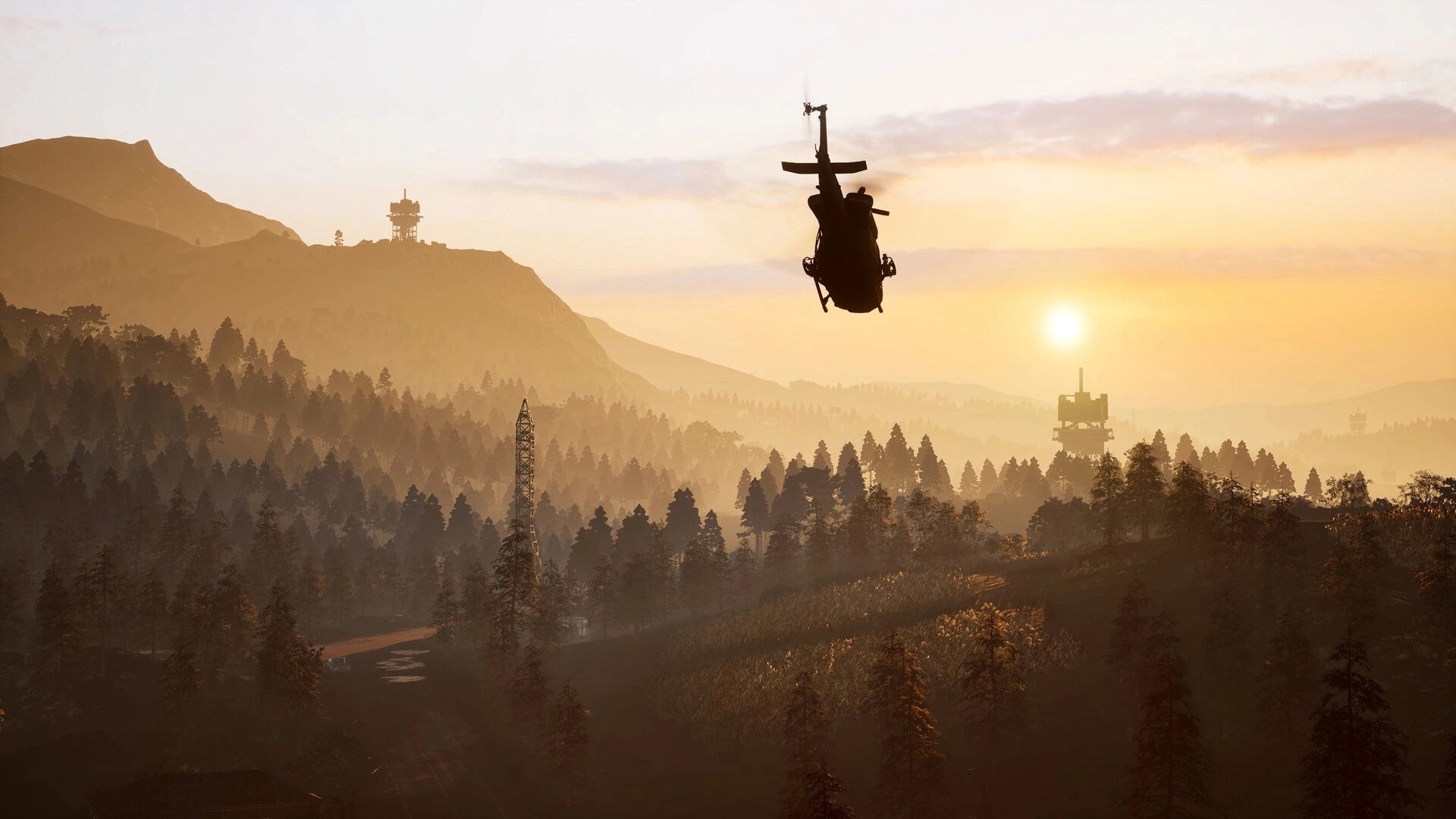 WARDOGS: Helicopter silhouette flying at sunset over forested mountains with distant radar towers.