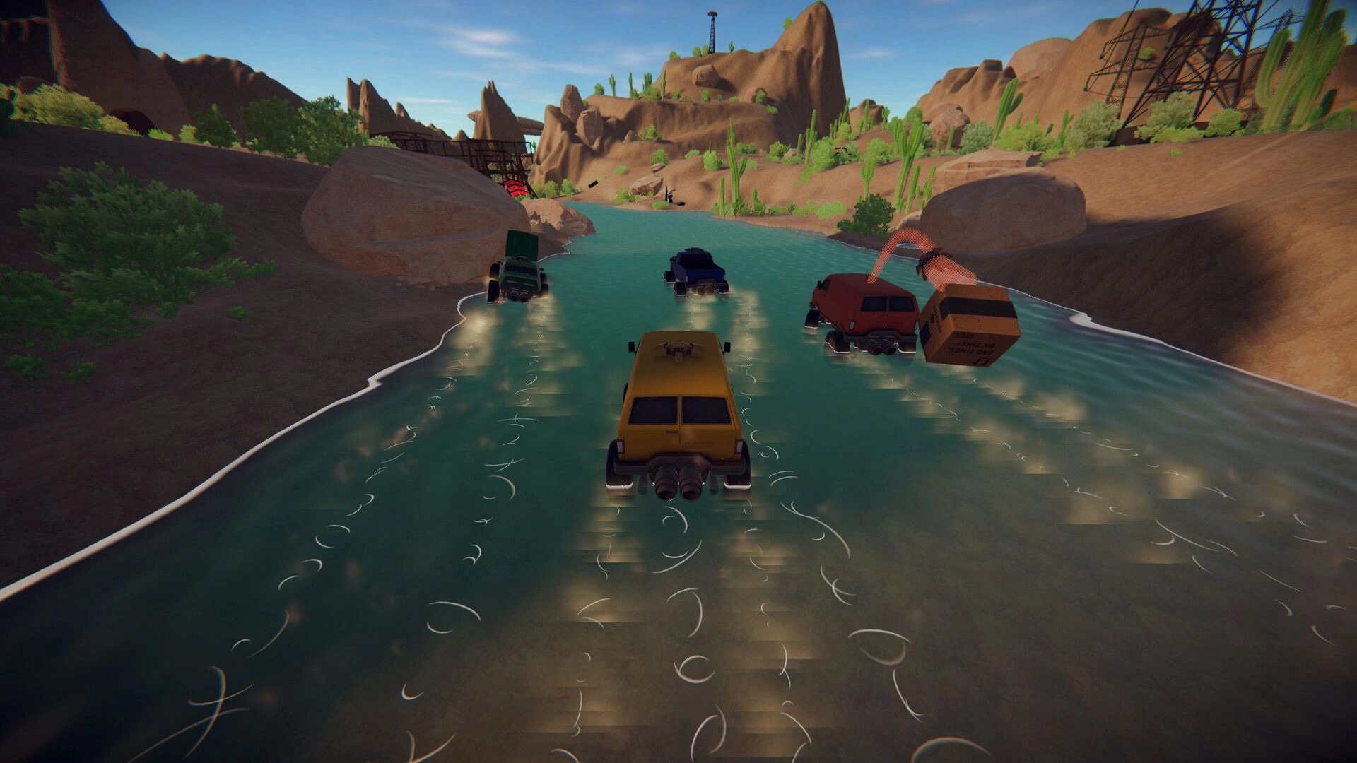 WITHOUT A HITCH: Four vehicles crossing a river in a desert canyon with rocky cliffs and sparse vegetation.